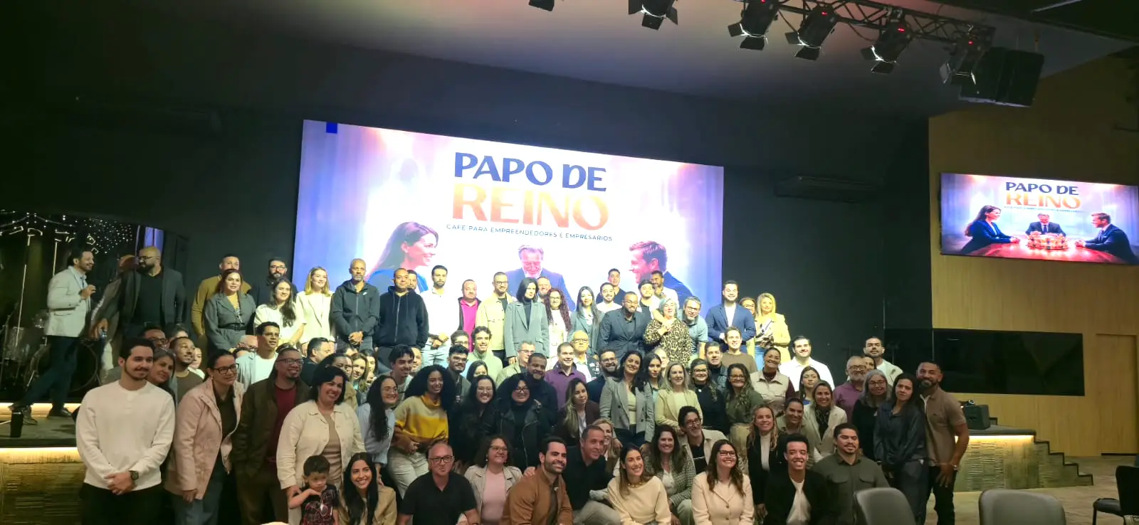 Os 86 empresários participantes reunidos no palco do Papo de Reino, diante do telão do evento
